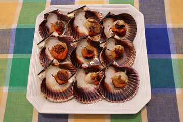 Portion of grilled scallops on a white tray and a checkered tablecloth
