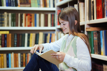 Student reading book on library floor