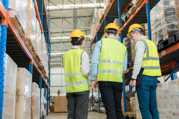 Three engineers inspecting goods in a large warehouse.