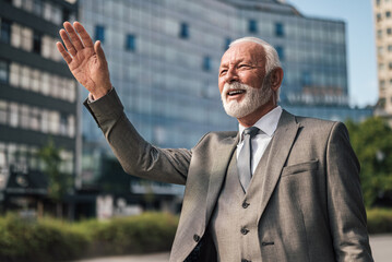 Smiling professional waving while hailing for taxi cab in the city against buildings.