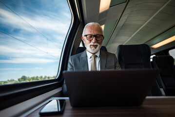 Smiling businessman working on laptop while traveling on the passenger train. - obrazy, fototapety, plakaty