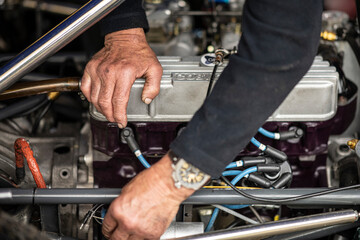 Mechanic on engine's classic racing car 
Mécanicien travaille sur un moteur de voiture de course...