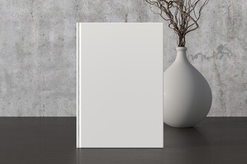 Vertical  book cover mock up standing on a dark wooden desk with concrete wall background.