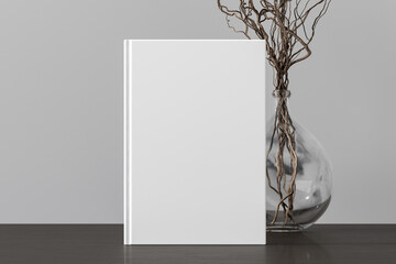 Vertical  book cover mock up standing on a dark wooden desk with white wall background.