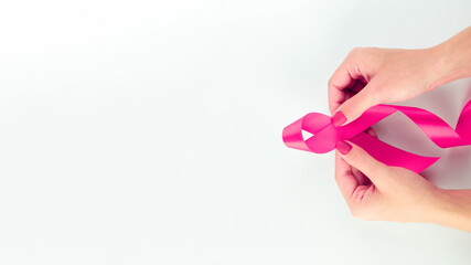 Cancer awareness. Health care symbol pink ribbon in woman hands on white background. Breast woman support concept. World cancer day.