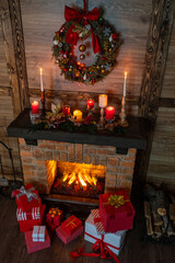 Many gift boxes near the Christmas fireplace in a festive interior of a Log Cabins with wooden walls. Mantelpiece with candles, Christmas wreath with bells