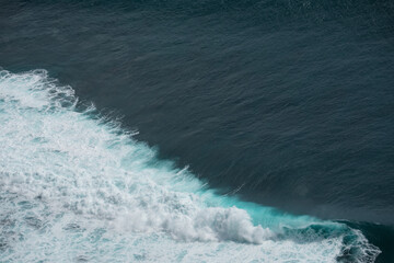 The waves of the ocean water meet with underwater pointed rocks