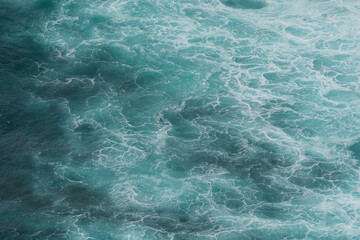 The waves of the ocean water meet with underwater pointed rocks