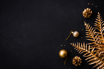 Christmas flat lay background with golden holiday decorations. Top view on black with copy space.