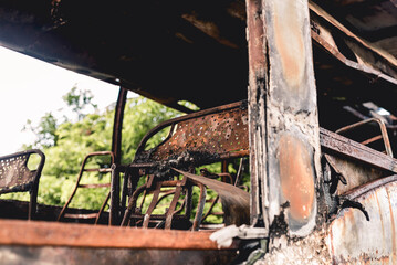 A burnt and totaled bus destroyed by fire abandoned at an empty lot.