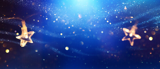Obraz na płótnie Canvas Christmas warm gold garland lights over dark background with glitter overlay