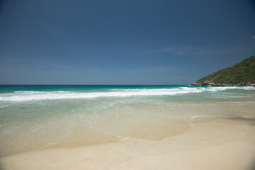 Fototapeta na wymiar Beach shore. White foam on the seashore. Tropical beach. Blue. Hot water. Clean sand.