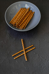 Crispy salt sticks in the bowl, on the black background