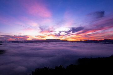 Aerial view of flowing fog waves on mountain tropical rainforest,Bird eye view image over the clouds sunrise sky, Amazing nature background with clouds and mountain peaks in Thailand