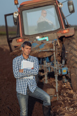 Farmer standing in front of tractor in field