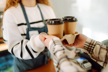 Fototapeta na wymiar Smiling barista- girl giving take away coffee cups to a customers. 