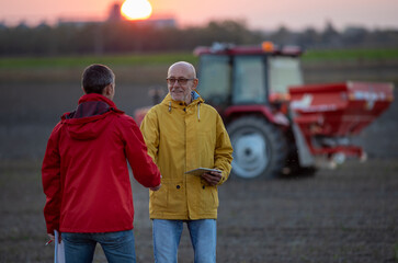 Farmers shaking hands in field in autumn