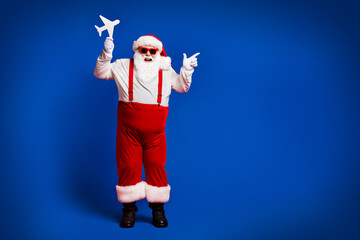 Full length body size view of his he attractive cheerful cheery fat Santa holding in hands paper plane showing copy space isolated bright vivid shine vibrant red burgundy maroon color background