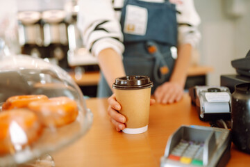 Smiling barista- girl giving take away coffee cups to a customers.  