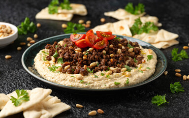 Hummus with spiced ground beef, olive oil, tomatoes and toasted pine nuts