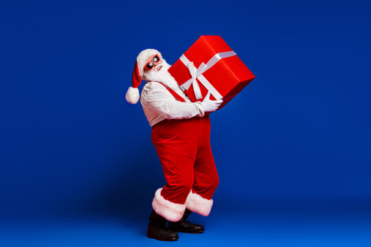 Full length body size view of his he attractive cheerful Santa father carrying big large giftbox fast delivery sale discount isolated bright vivid shine vibrant red color background