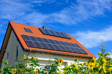 Modernes Solardach vor blauem Himmel mit Sonnenblumen im Vordergrund