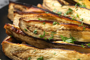 Roast eggplant, aubergine with herbs on black plate