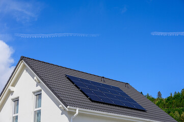 Solarzellen auf modernem Einfamilienhaus vor blauem Himmel