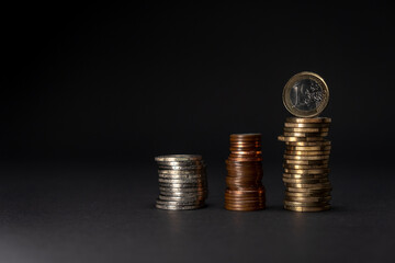 Euro coins stacked on a dark background. Euro coins saving concept side view. Copy space.