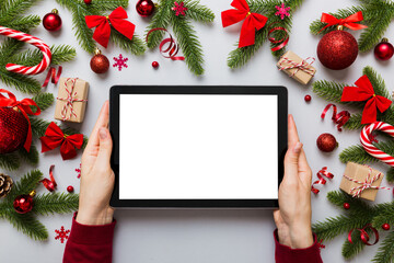 Christmas online shopping from home, female hands holding tablet pc with blank white display top view. woman hand holding tablet with blank screen, Christmas tree and gifts on background - Powered by Adobe