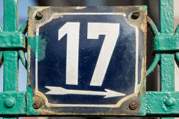 Weathered grunge square metal enameled plate of number of street address with number 17