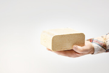 Hand hold fuel briquette made from sawdust on light brown background. Alternative fuel, bio fuel,...