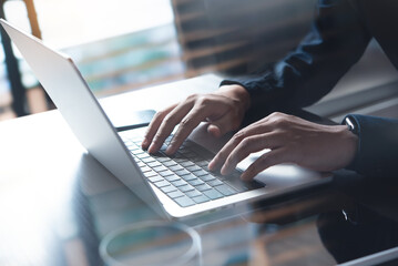 Business man hands typing on laptop computer keyboard, searching information, surfing the internet on dark office desk, distance job, online working, business and technology concept