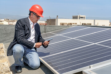Ingegnere verifica le condizioni di un impianto fotovoltaico sul tetto di una casa con un tablet in...