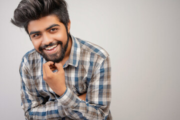 young hispanic bearded man wearing plaid shirt over white background with positive expression, has broad interested smile. Look there, please.looking for something or found something