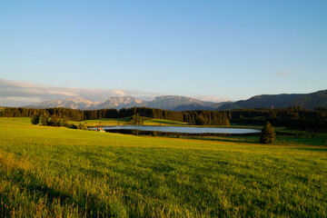 hiking trail overlooking scenic alpine lake Attlesee and the sun-drenched vast, lush, green meadows...