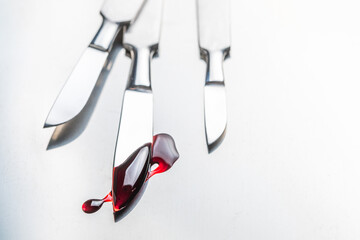 Surgical steel scalpels with blood on stainless steel plate.