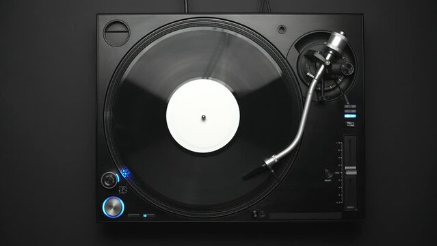 Disc jockey turntable plays music. Retro DJ record player in overhead video clip. 