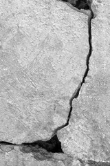 Big crack on gray wall, abstract image of vertical cleft. Close-up. Vertical black and white photo. Selective focus.
