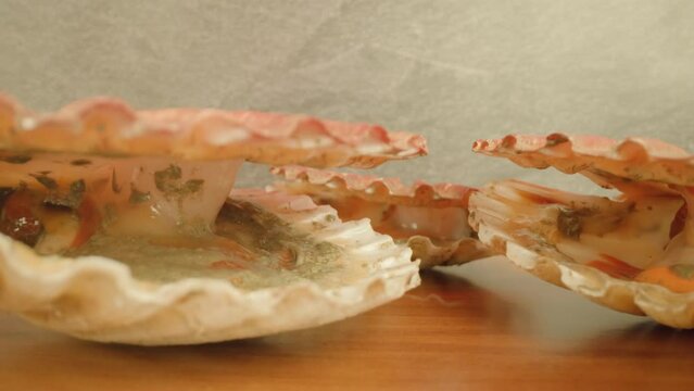 Live bivalve mollusks with pink-colored muscle open shells lying on wooden table at bright studio illumination extreme closeup push in