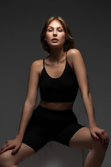 Young woman in black shorts and top posing in the studio