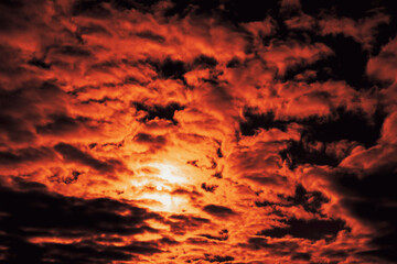 Cloudy sky with cumulus clouds at sunset. Twilight saturated with cochineal color. The solar disk is barely visible. narrow focus.