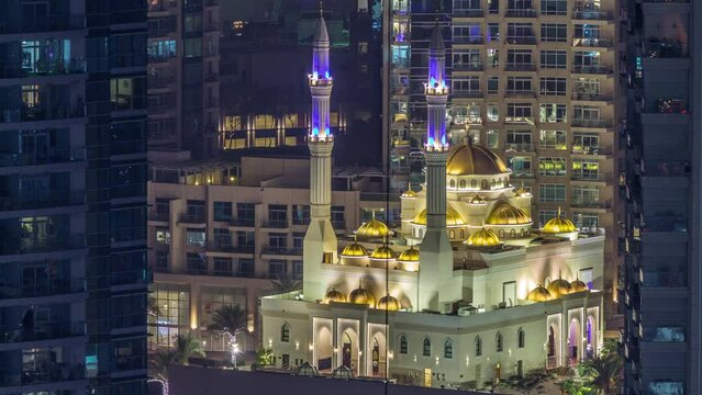 Al Raheem mosque between skyscrapers day to night transition timelapse on the marina walk in Dubai Marina, Dubai, UAE. Aerial top view at evening after sunset