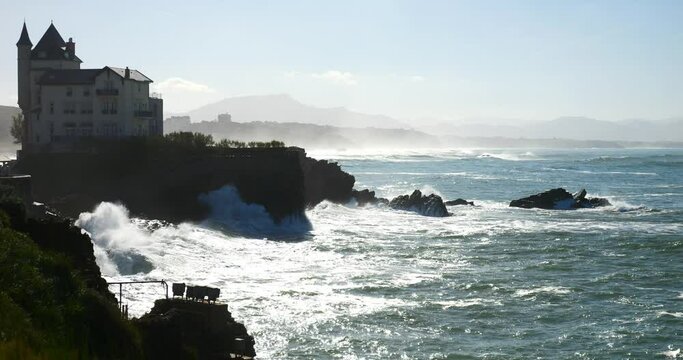 Swell breaking on the beach of Biarritz in the Basque Country with the lighthouse on the horizon (in slow motion)