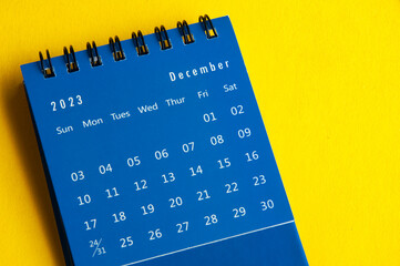 December 2023 blue desk calendar on yellow cover background with customizable space for text. Year...