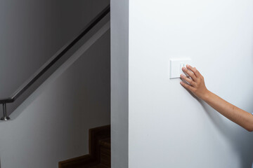 An energy-saving notion is demonstrated by a woman turning out the lights on the sidewalk up the stairs. © Parkin