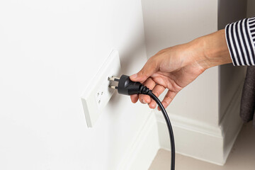 Unplug or plugged in concept in the wall-mounted electrical outlet