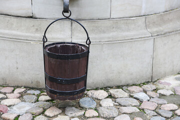 An antique medieval bucket hangs on a well.