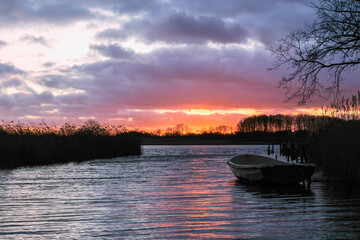 Small fishing boat at the lake at sunset in winter.