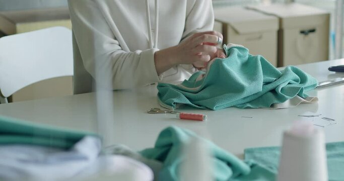 Young dressmaker woman sews clothes by her hands. Fashion business concept